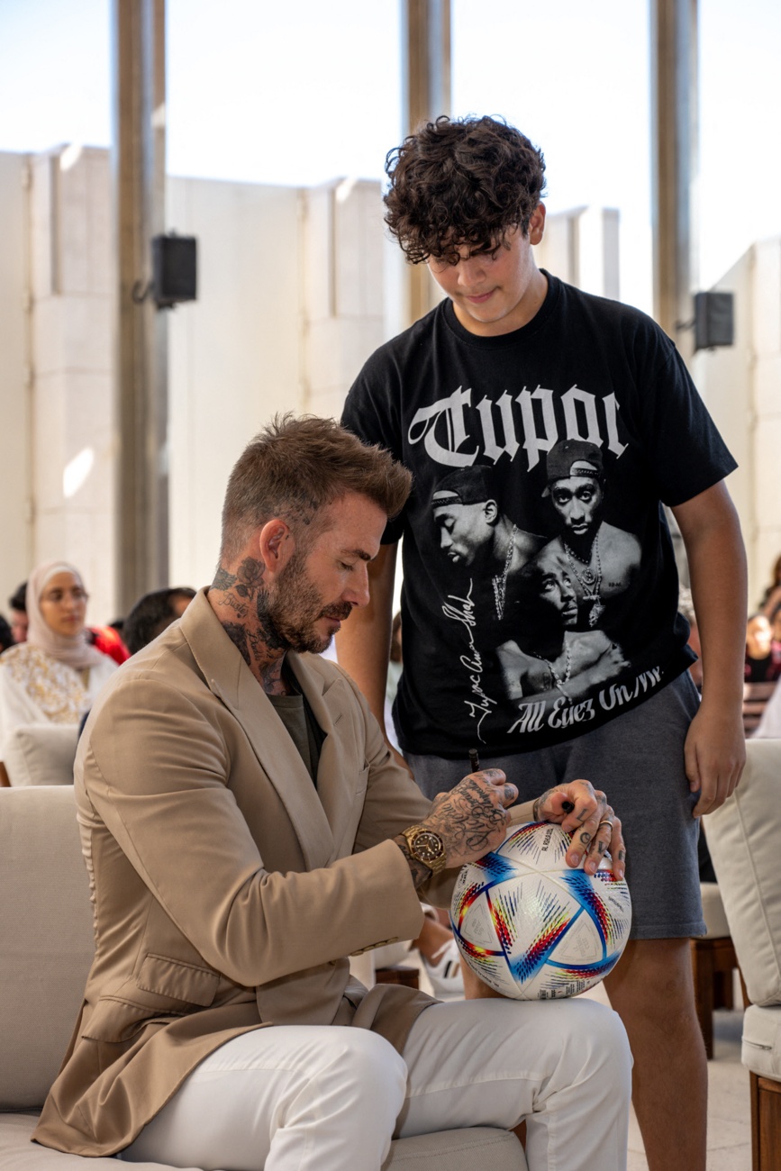 David Beckham signe un ballon pour un fan lors du lancement de la série ''Save Our Squad'' au Qatar